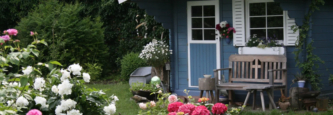 Blaues Gartenhaus mit Rosen