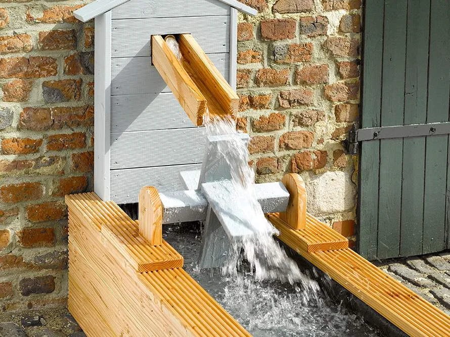 Hölzerner Gartenbrunnen an Backsteinmauer