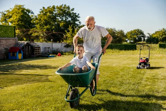 Senior schiebt Kind in Schubkarre
