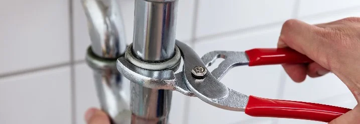 Person nutzt Rohrzange an Siphon