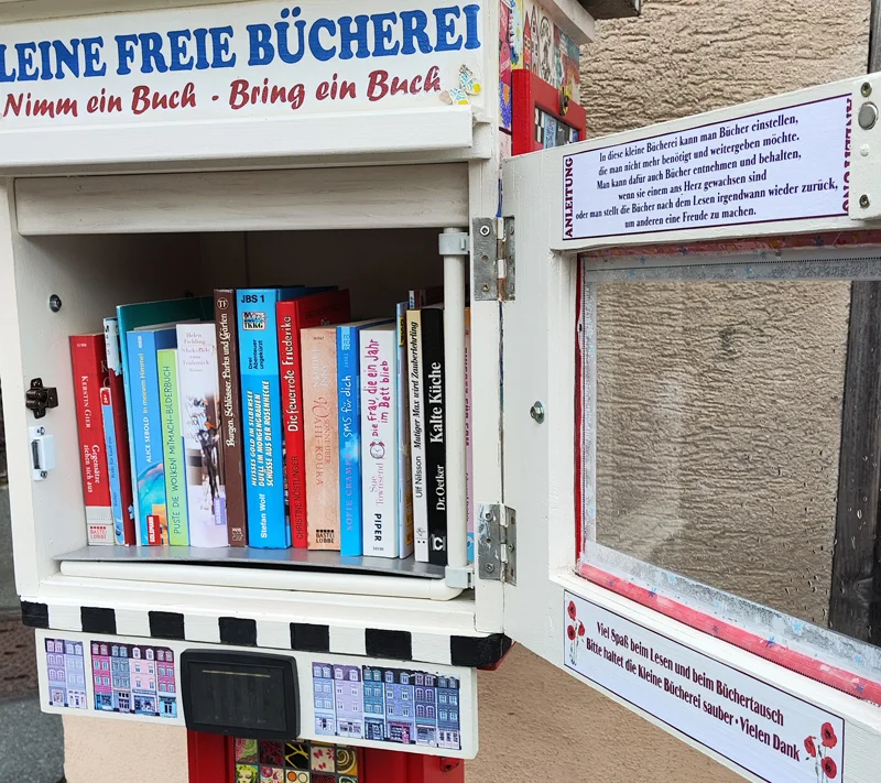 Ein weißer, offener Bücherschrank, der mit bunten Büchern gefüllt ist.