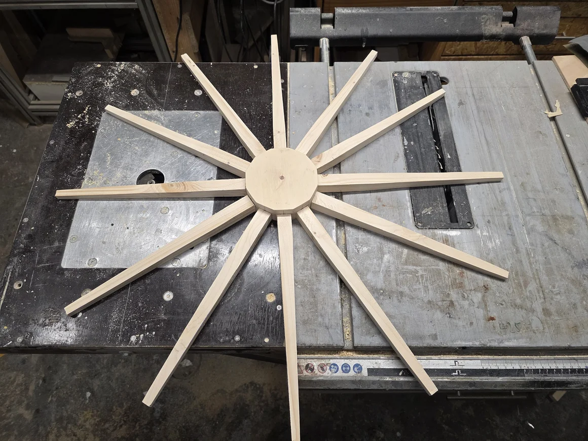 Ein Holzrad mit zwölf Speichen liegt auf einer Tischkreissäge.