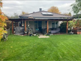 Gartenhaus mit überdachter Terrasse und grünem Rasen