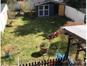 Garten mit Rasenmäher und Gartenhaus
