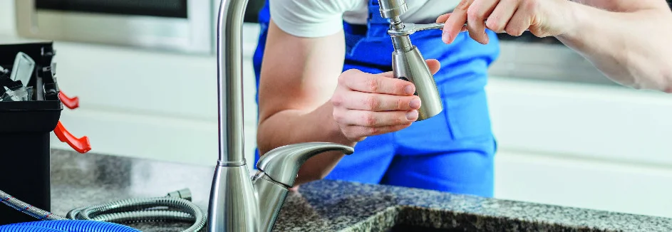 Person montiert Wasserhahn mit Schraubenschlüssel.