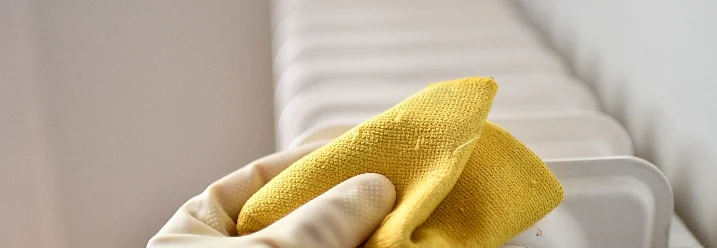 Hand reinigt Heizung mit Lappen