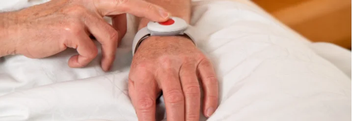 Person drückt roten Knopf auf einem Armband
