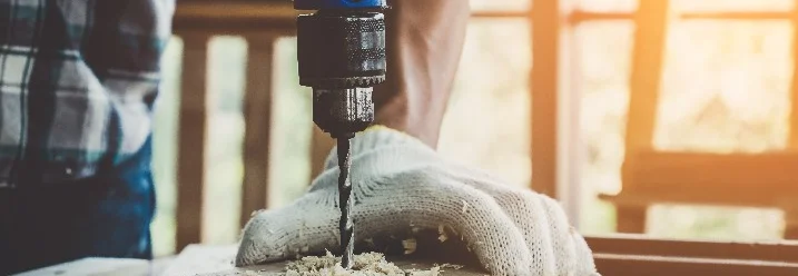Person bohrt mit Bohrmaschine in Holz