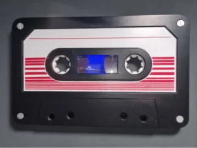 Eine schwarze Audiokassette mit rot-weißen Streifen.