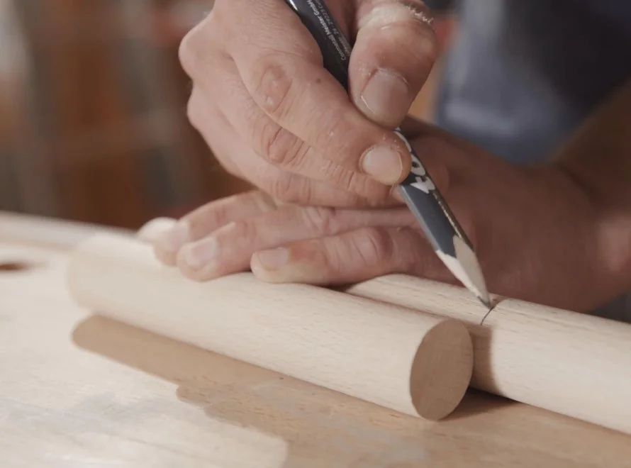 Person markiert Holz mit Bleistift