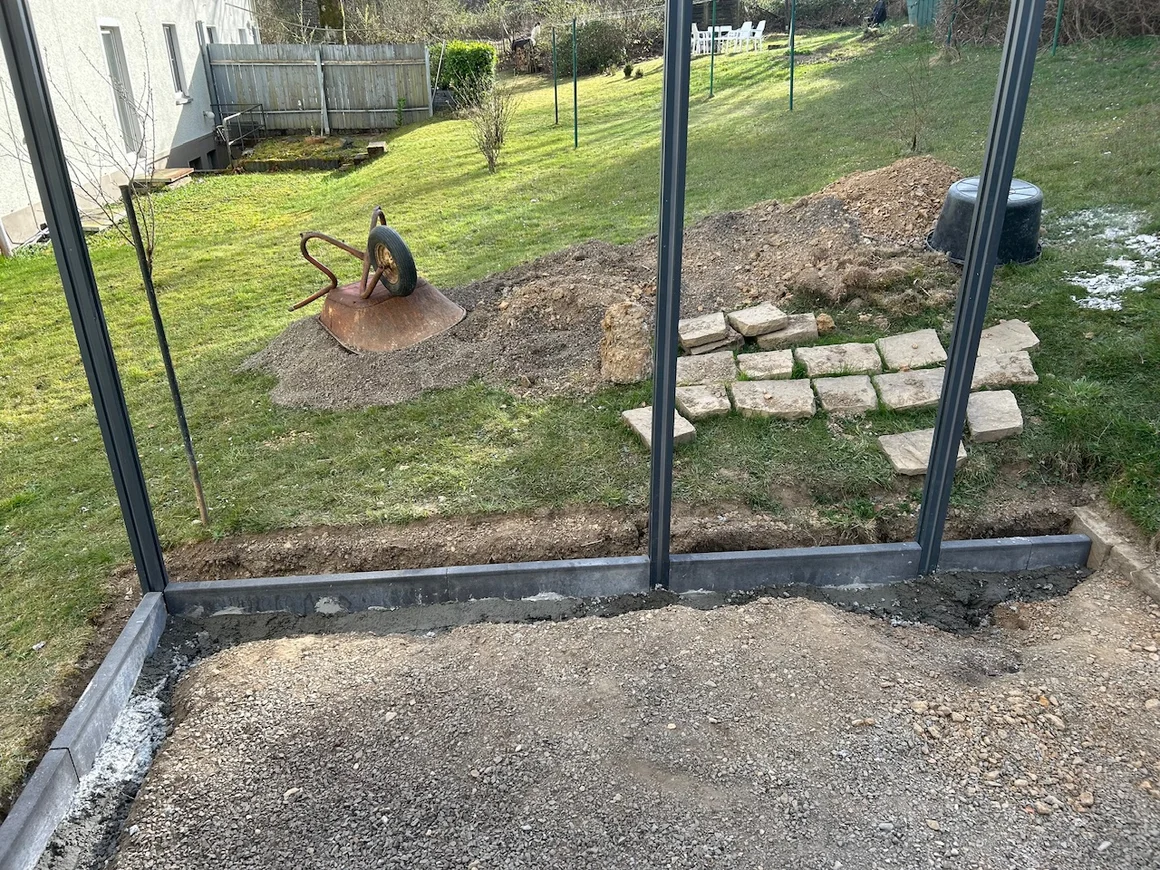 Eine Baustelle im Garten mit einer umgedrehten Schubkarre auf einem Erdhaufen.