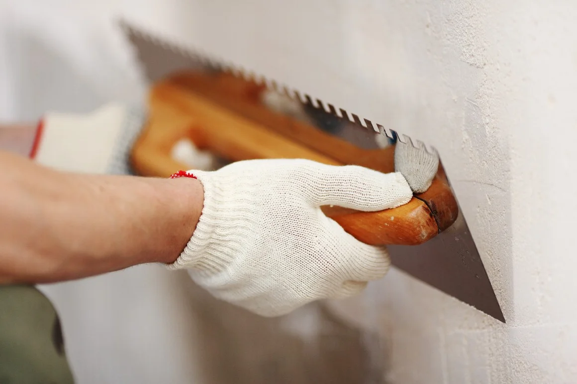 Person verputzt Wand mit Kelle