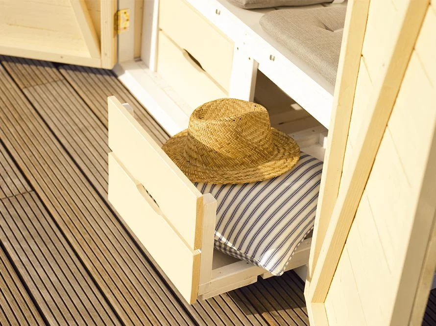 Offene Schublade mit Sonnenhut und Kissen