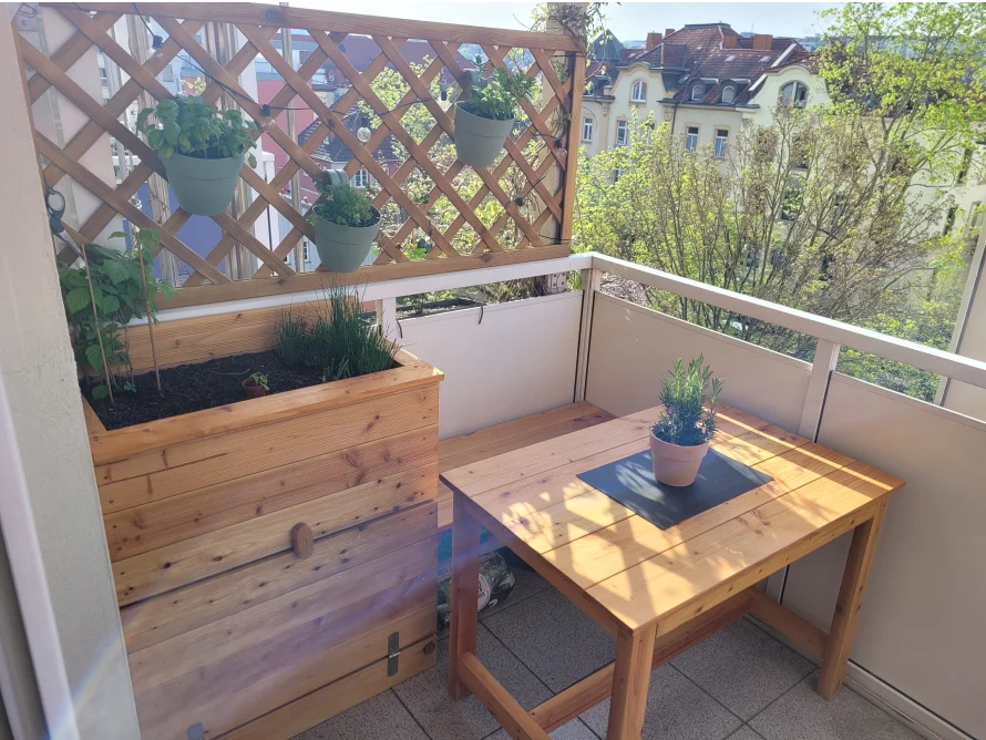 Sonniger Balkon mit Holzmöbeln und Pflanzen