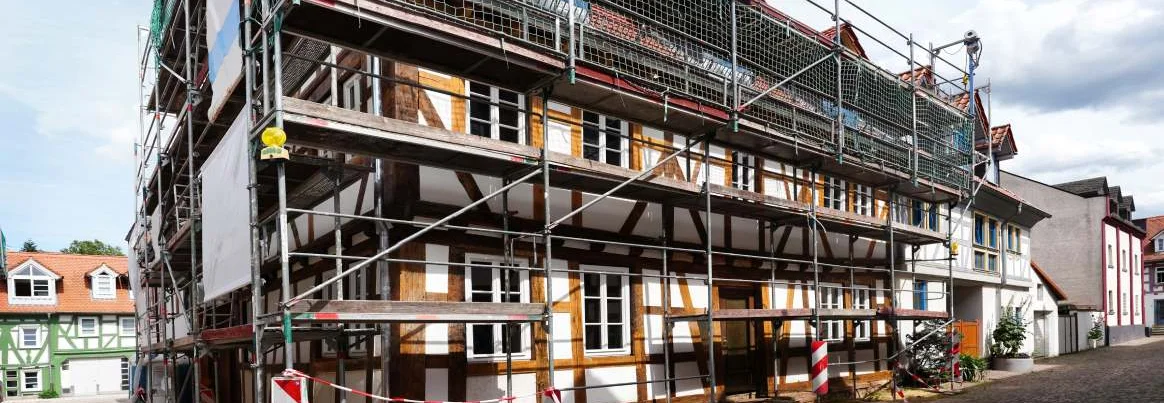 Ein Fachwerkhaus wird mit einem Gerüst saniert.