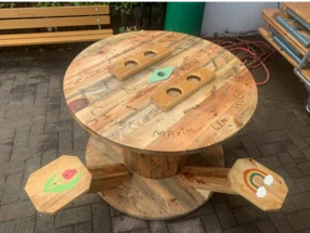 Ein runder Tisch und zwei passende Hocker aus Holz.
