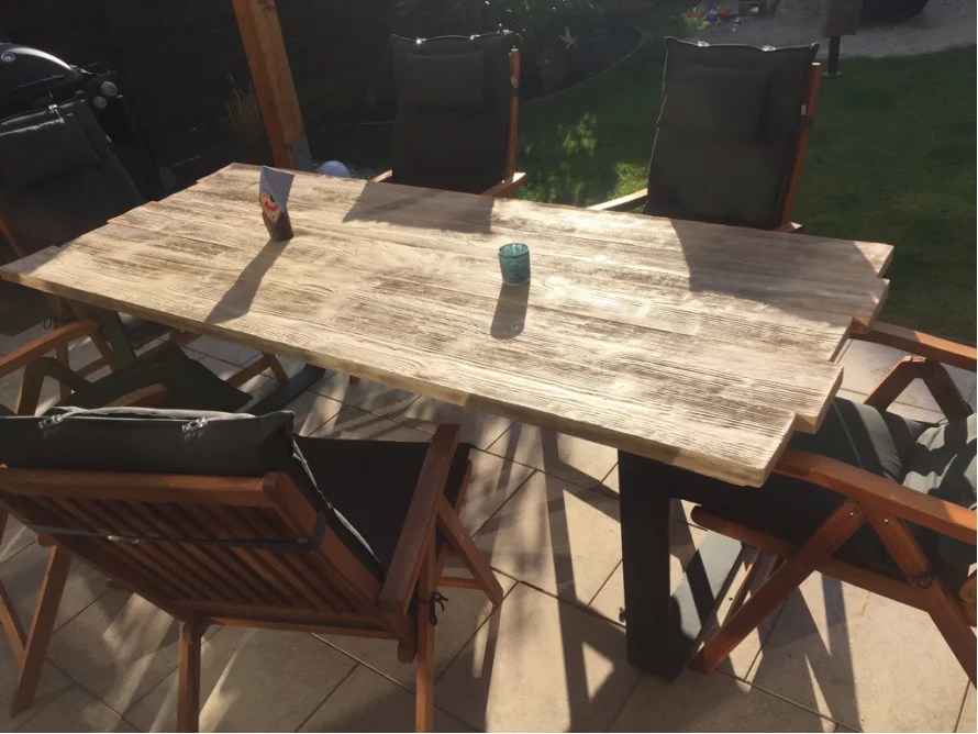 Holztisch mit Stühlen auf einer Terrasse