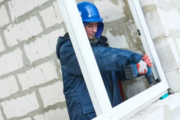 Person mit Helm und Bohrer bei der Arbeit