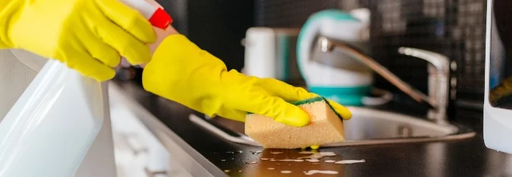 Person reinigt Arbeitsplatte mit Schwamm