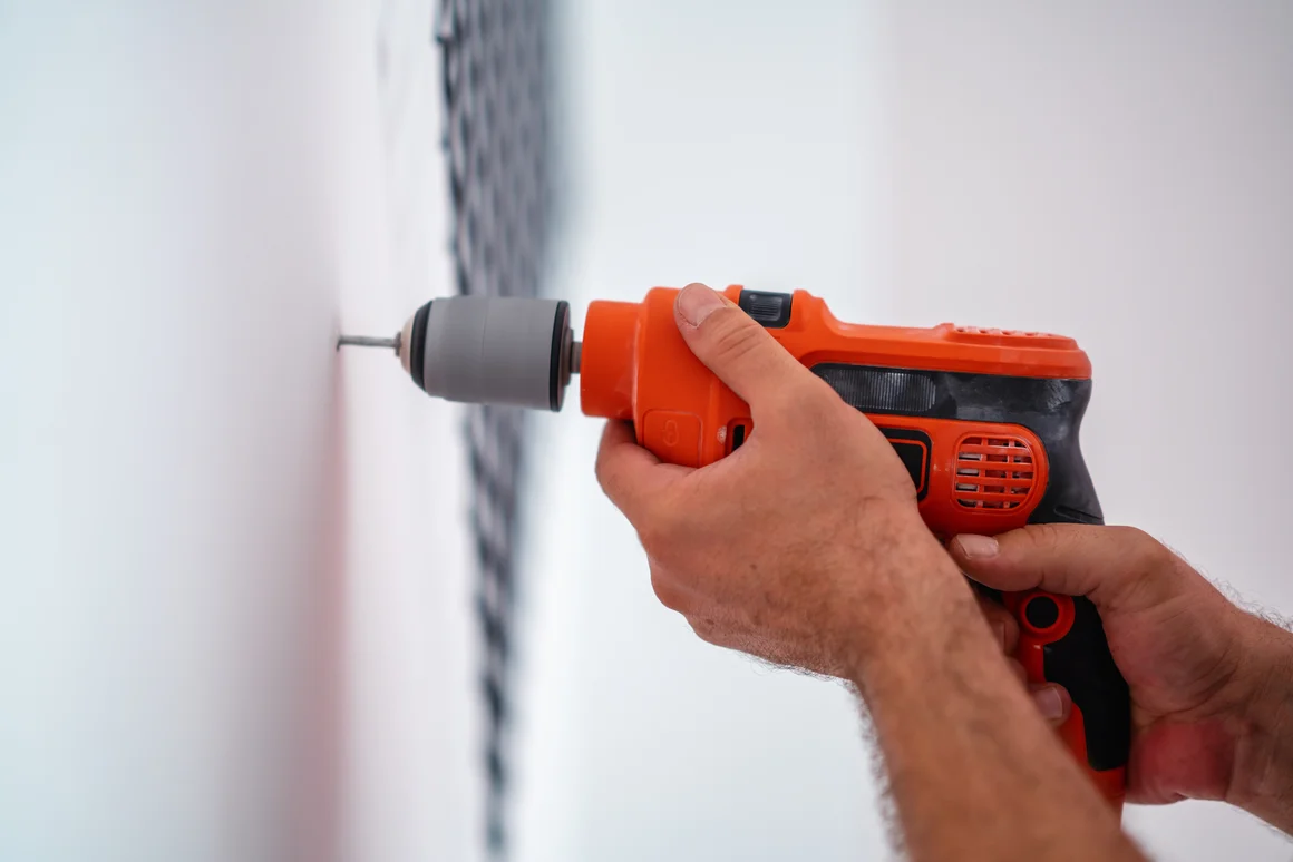 Person bohrt mit Bohrmaschine in Wand