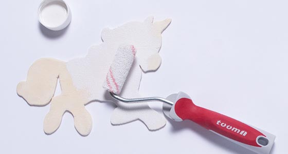 Einhorn aus Holz wird mit einer Farbrolle bemalt
